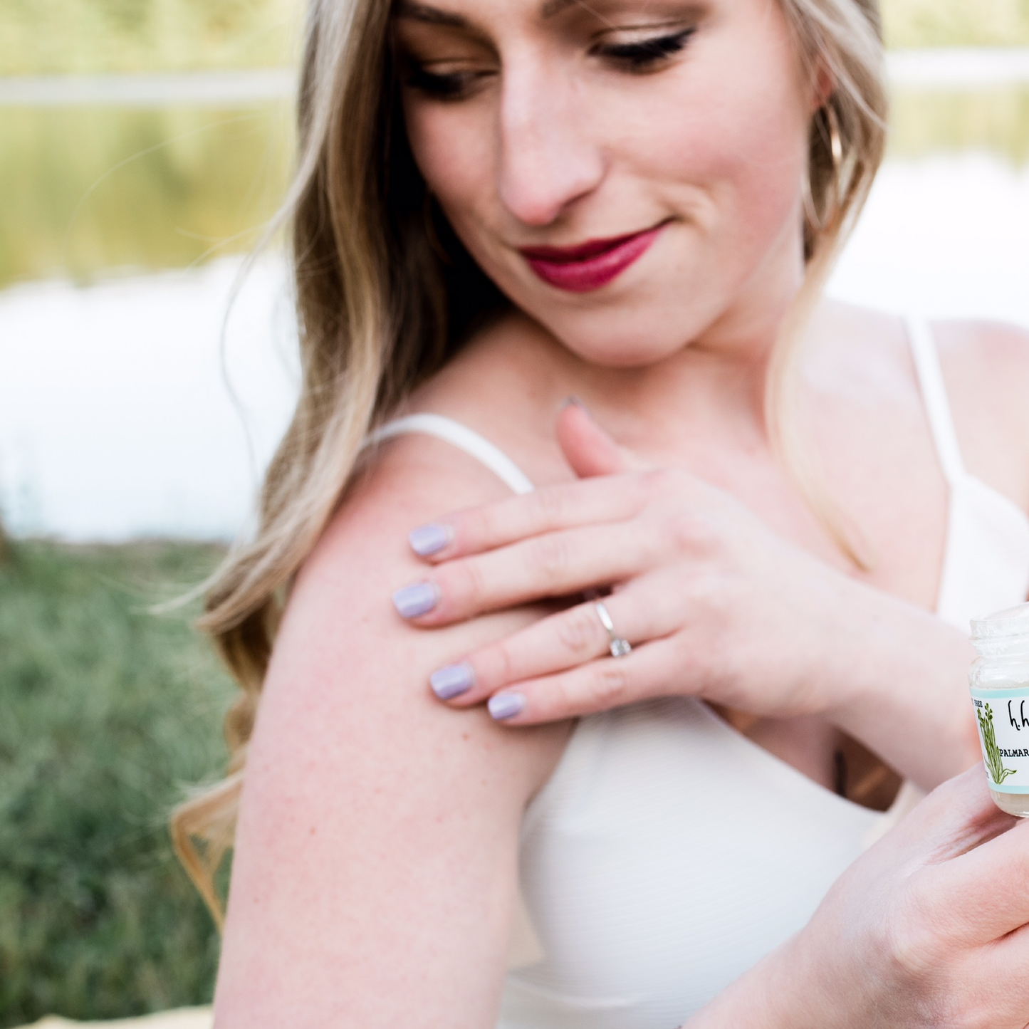 Woman outside holding H. Honeycup body scrub showing soft shoulder